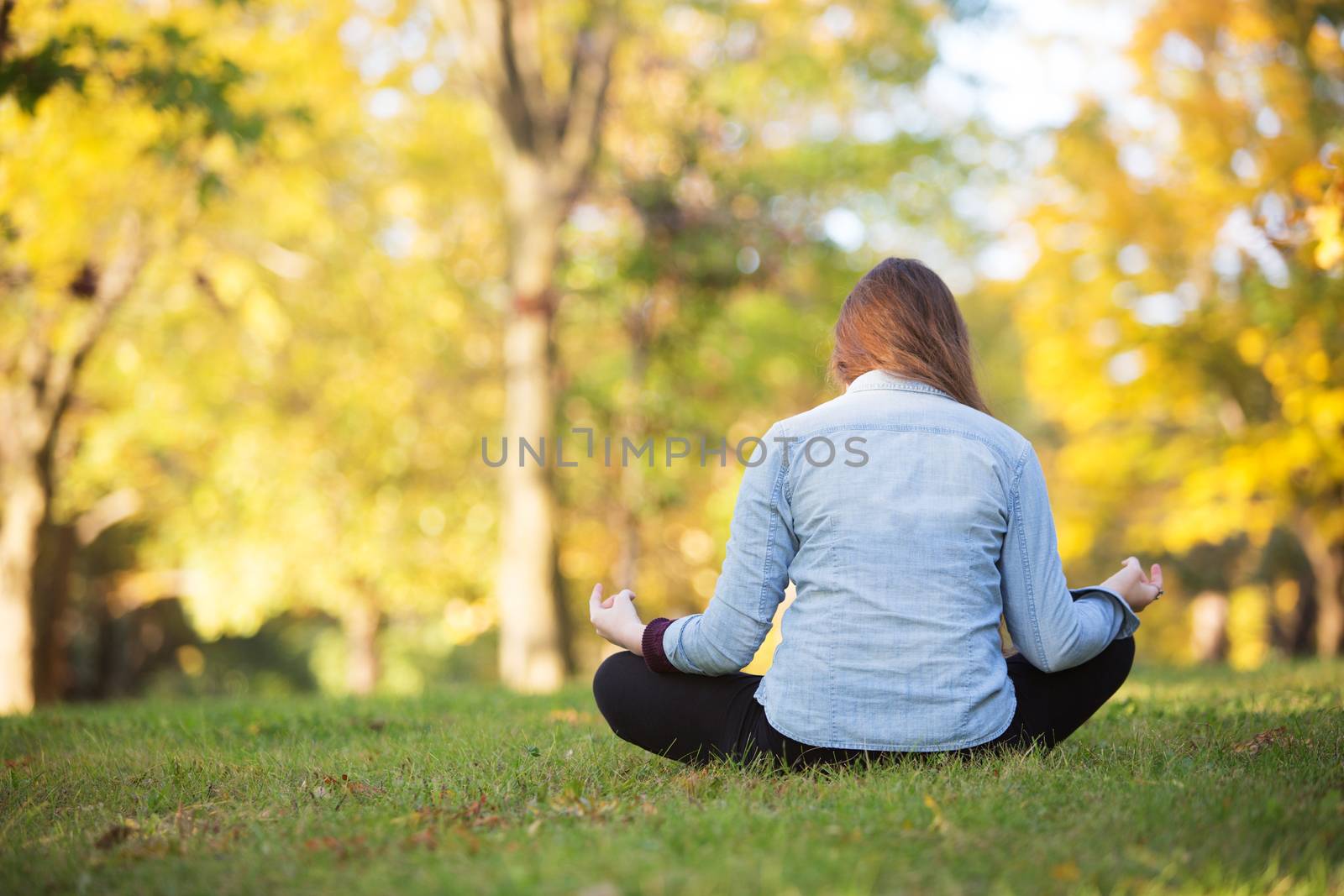 Rear view of woman sitting in meditation pose outdoors