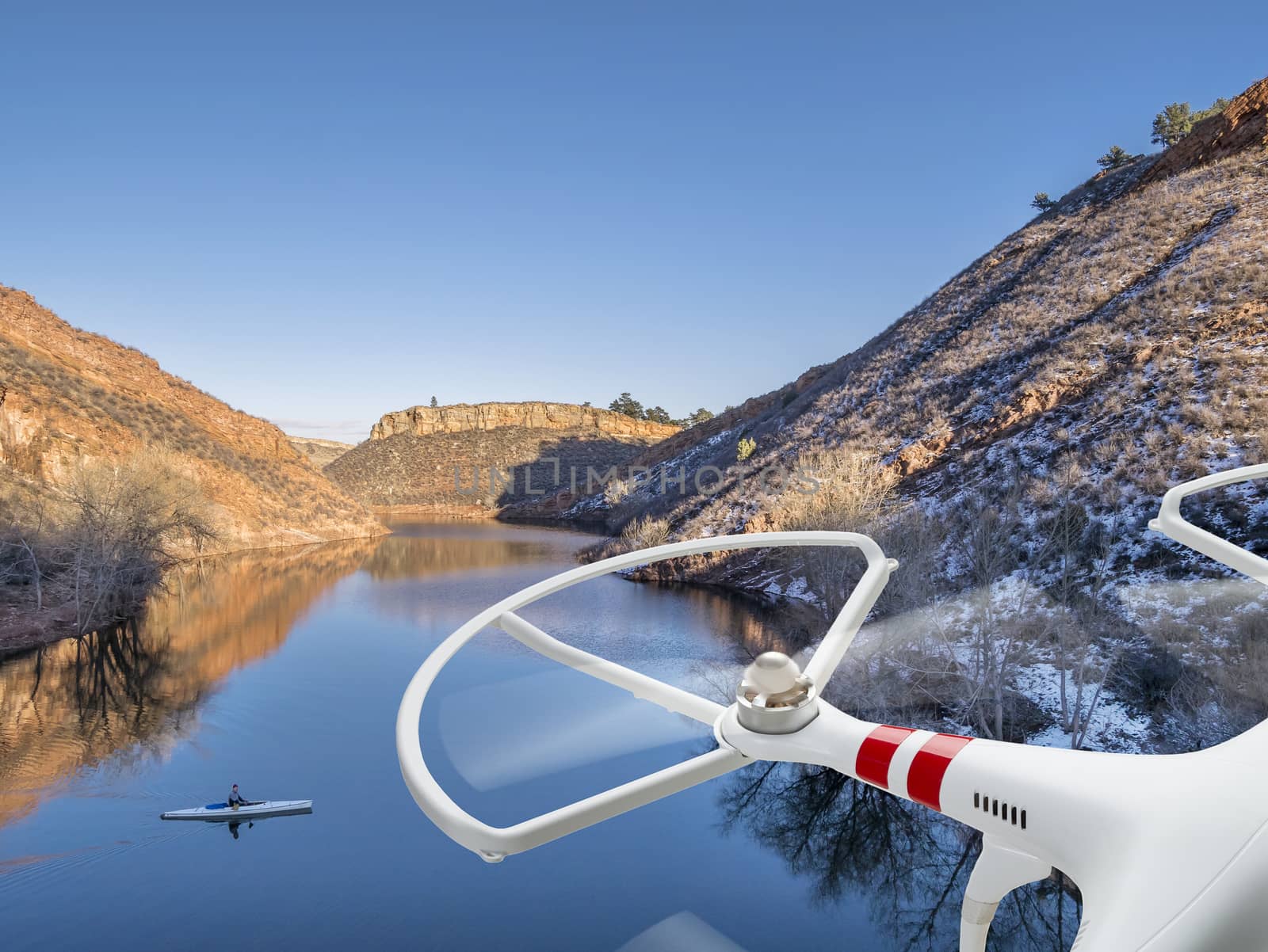 drone flying over lake with canoe by PixelsAway