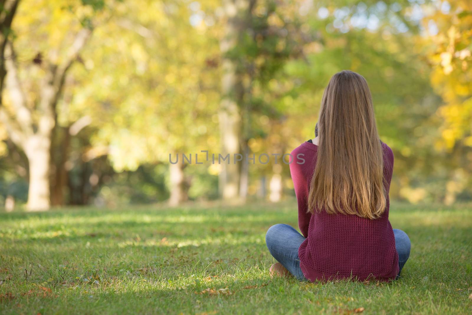 Unidentifiable woman sitting cross legged on grass
