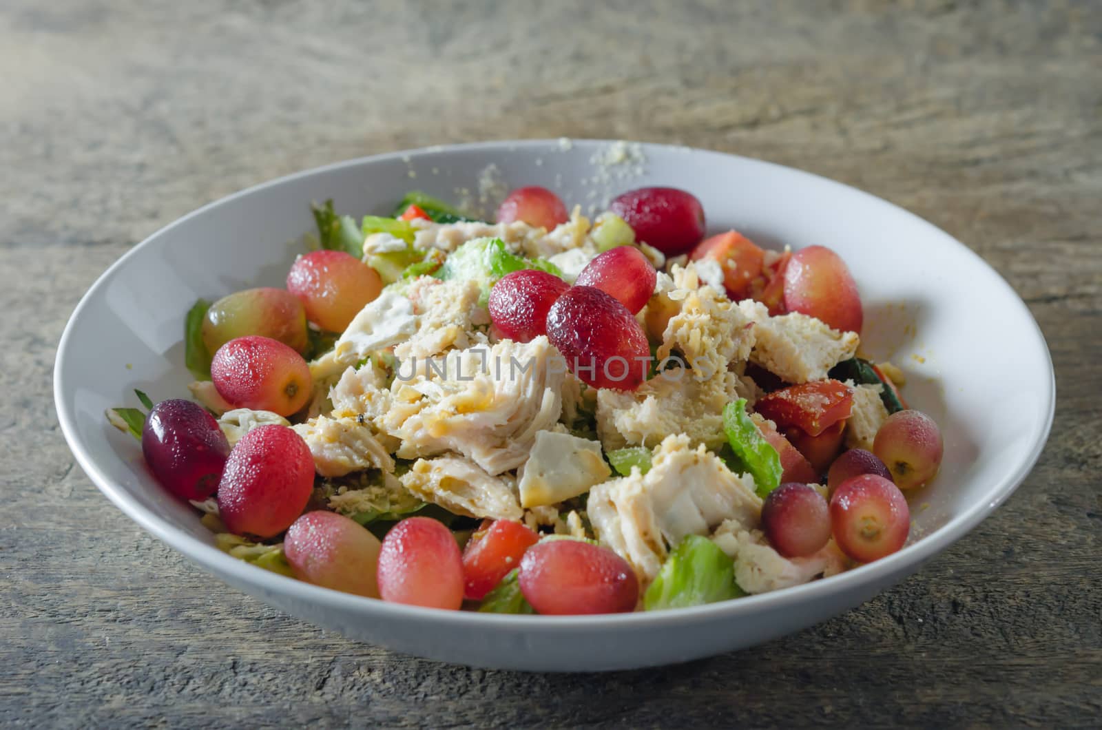 Mix salad with grapes and chicken on white dish