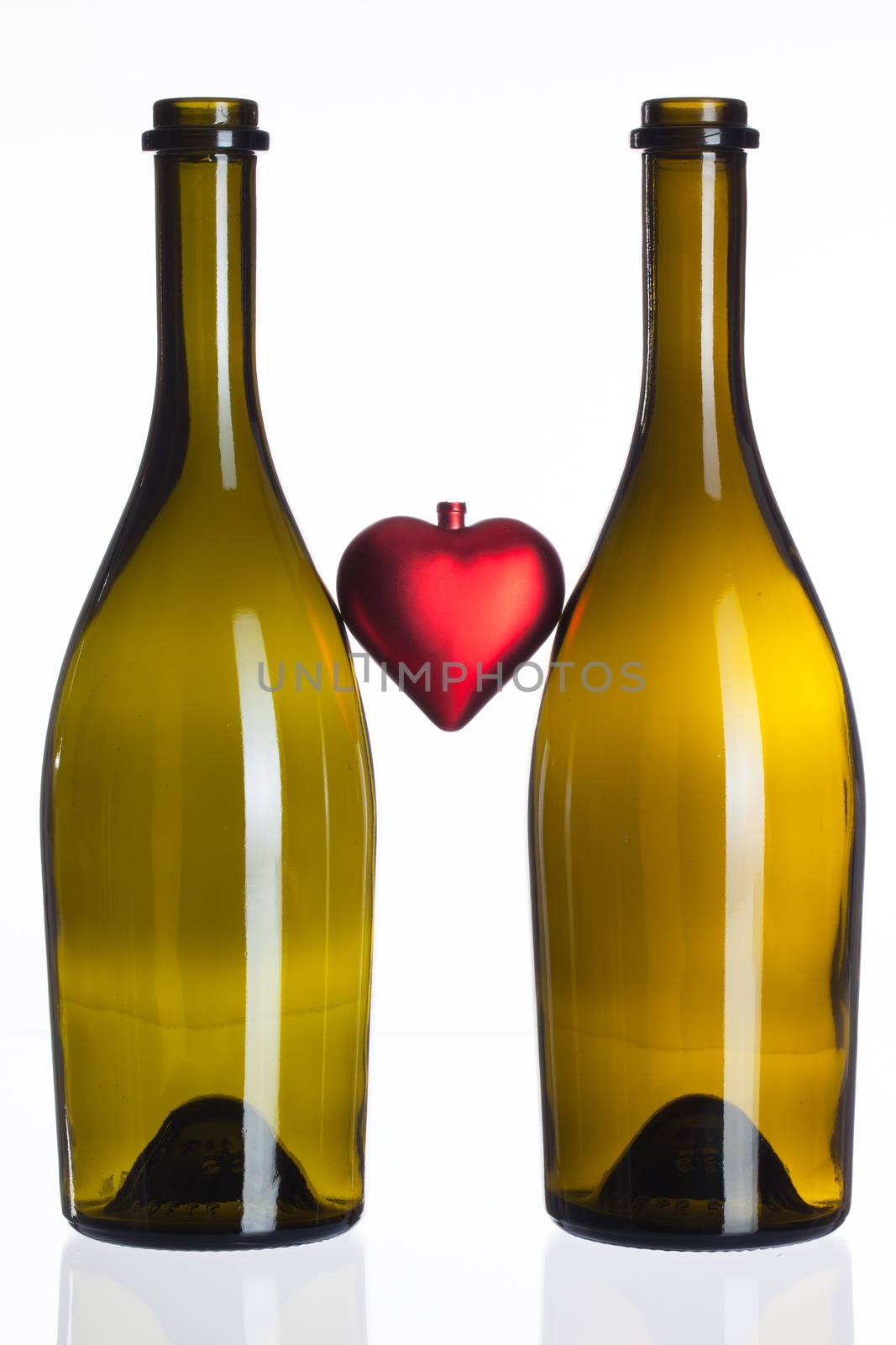 Empty bottles of wine and red heart on a glass table