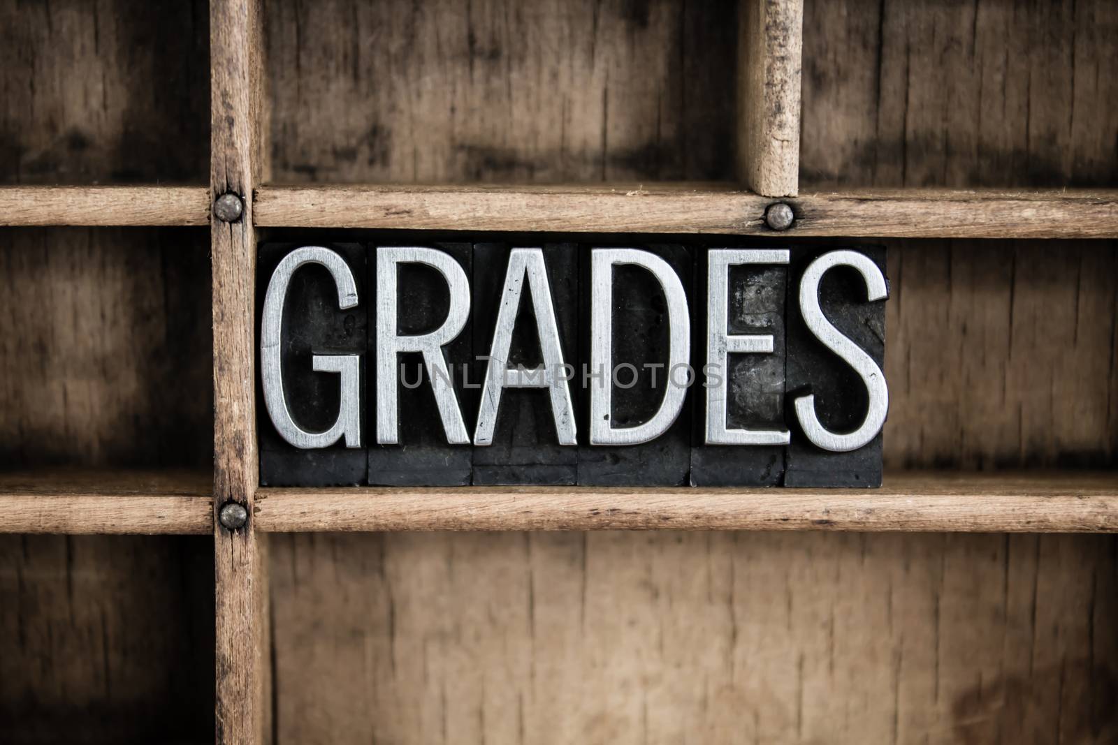 The word "GRADES" written in vintage metal letterpress type in a wooden drawer with dividers.