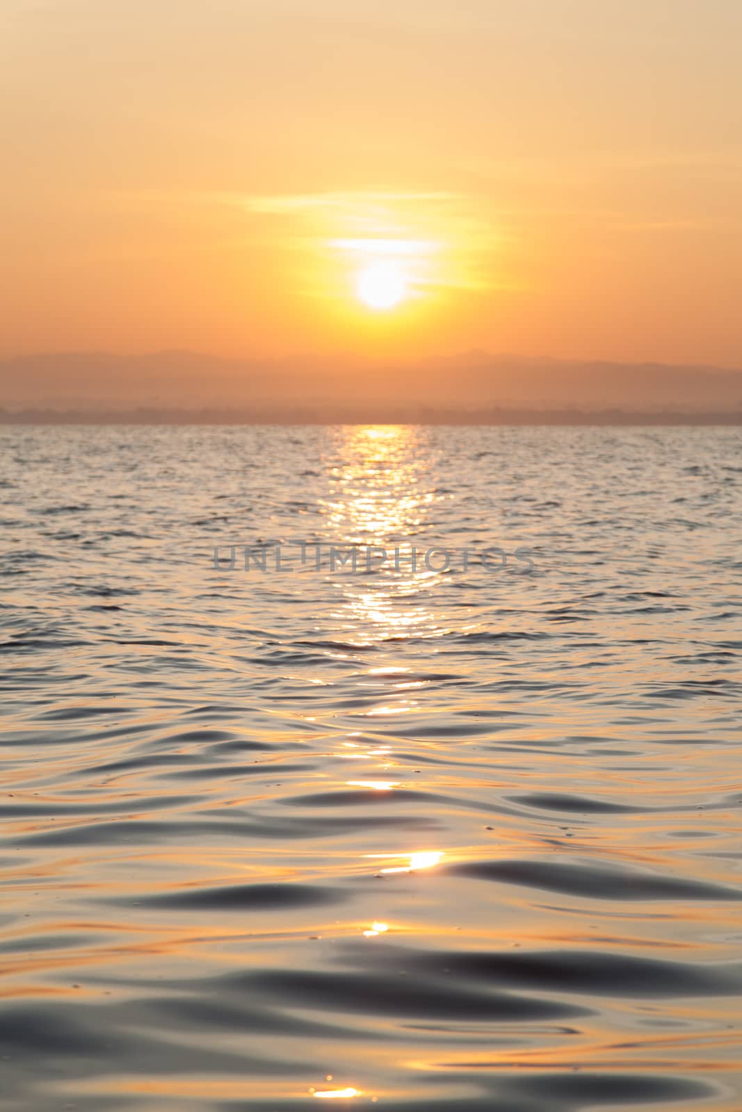 The sun rising in the morning. In front of a lake reflecting sunlight.