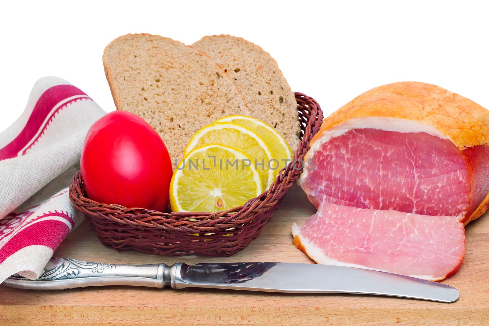 On a cutting Board is ham, bread, lemon and tomato. Presented on a white background.