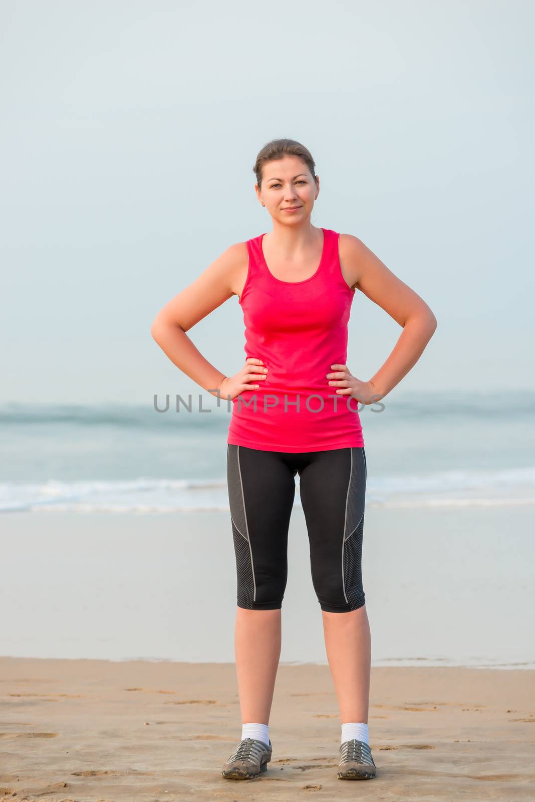 Girl in sportswear before exercise on the beach by kosmsos111