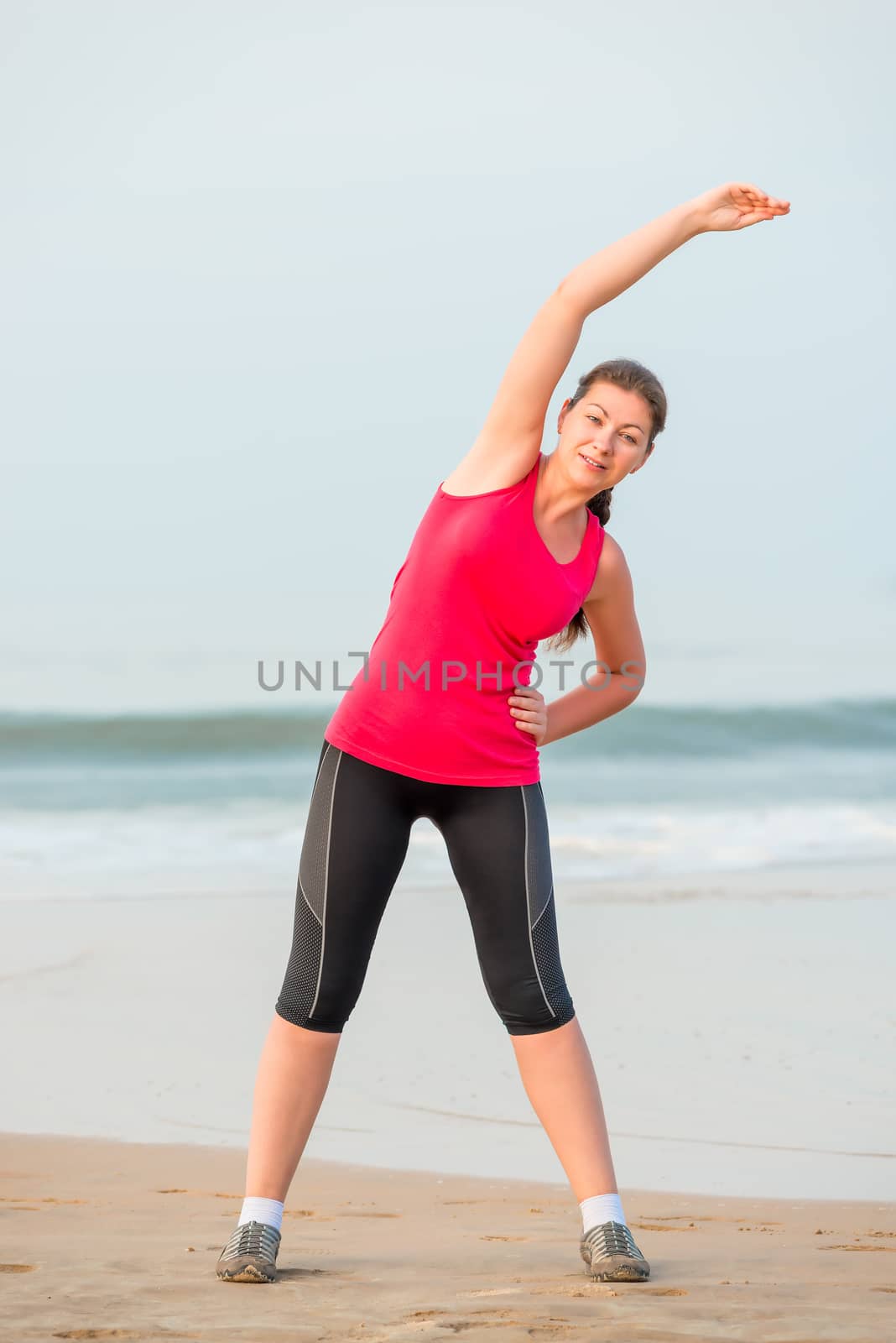 young athletic girl warming up near the sea by kosmsos111