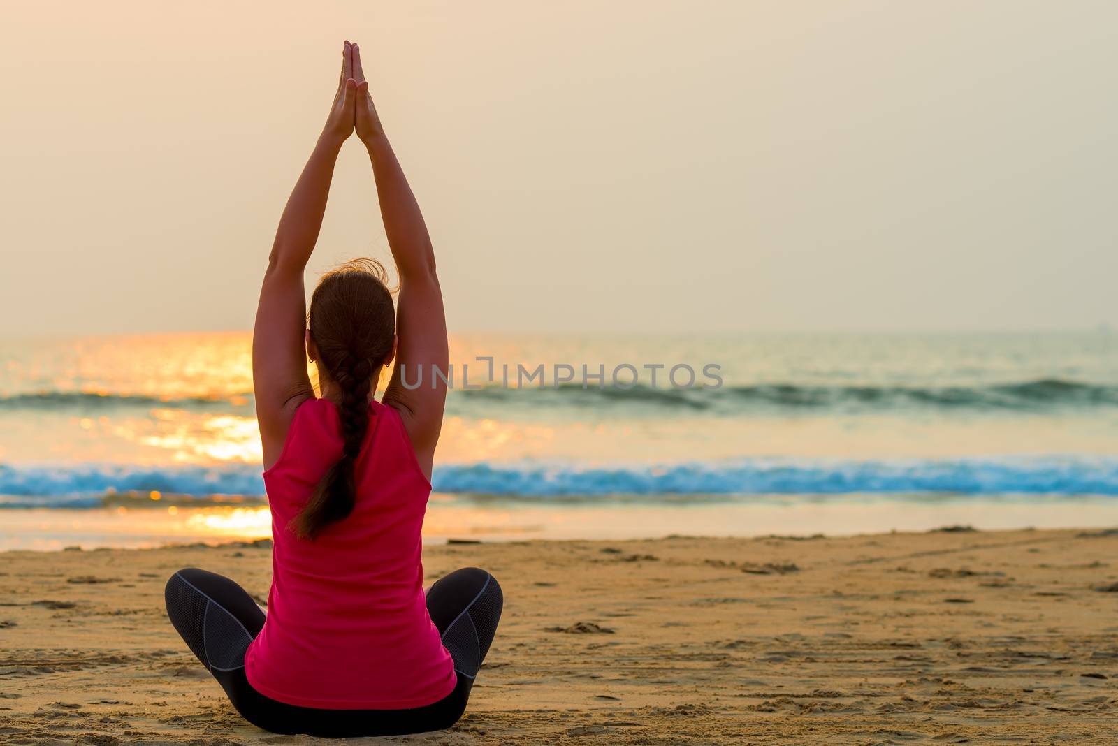 woman relaxes by the ocean sitting in the lotus position