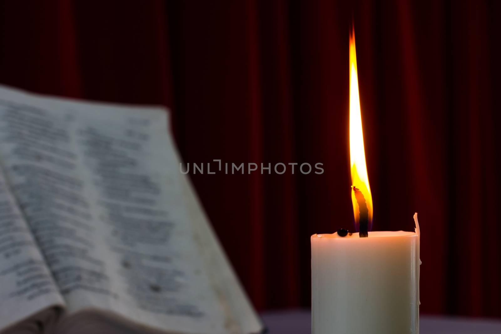 bible open on a table with candle in the dark. Perfect for religion, easter and christmas themes. candle fucused
