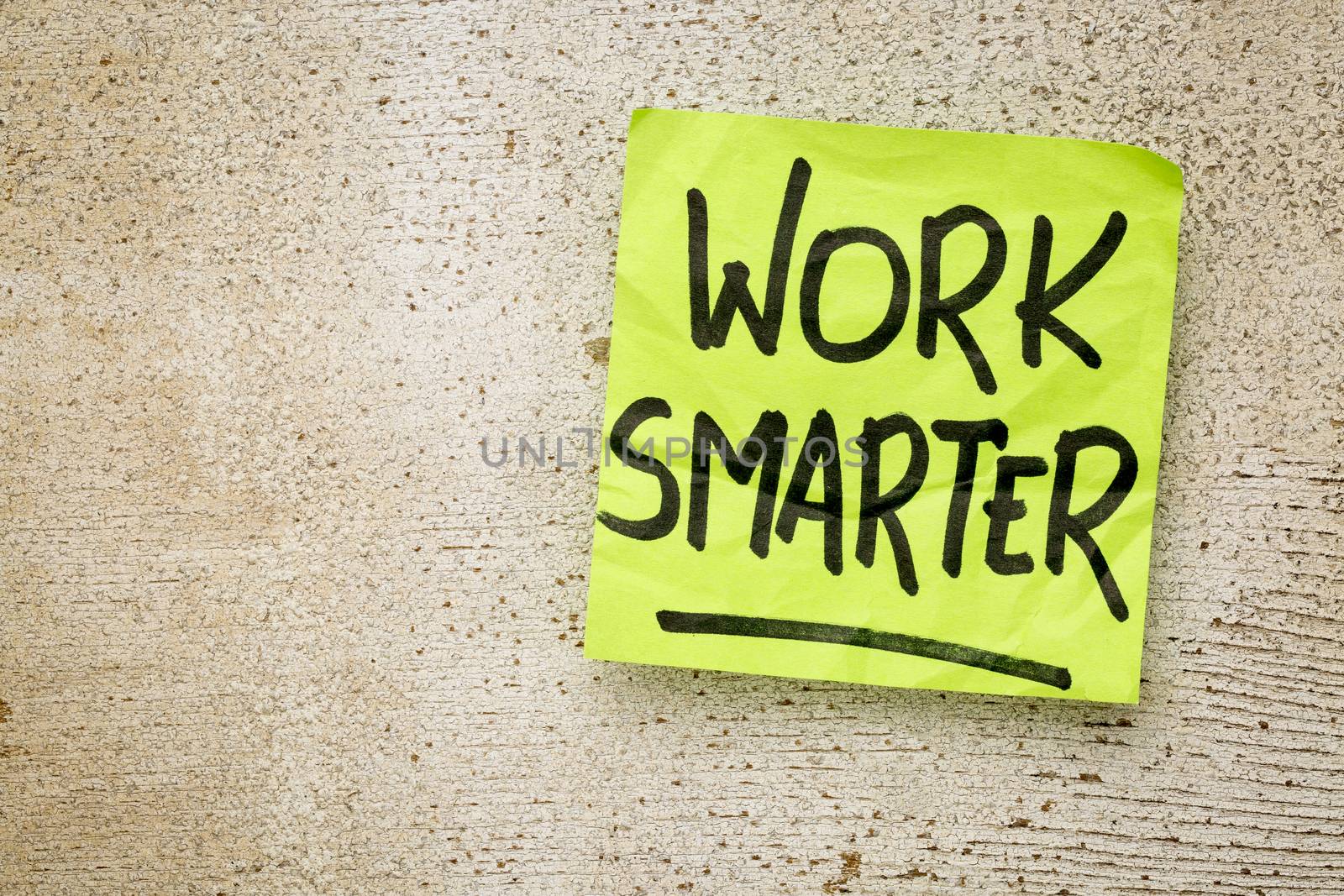 work smarter reminder on a green sticky note against rustic barn wood p productivity concept