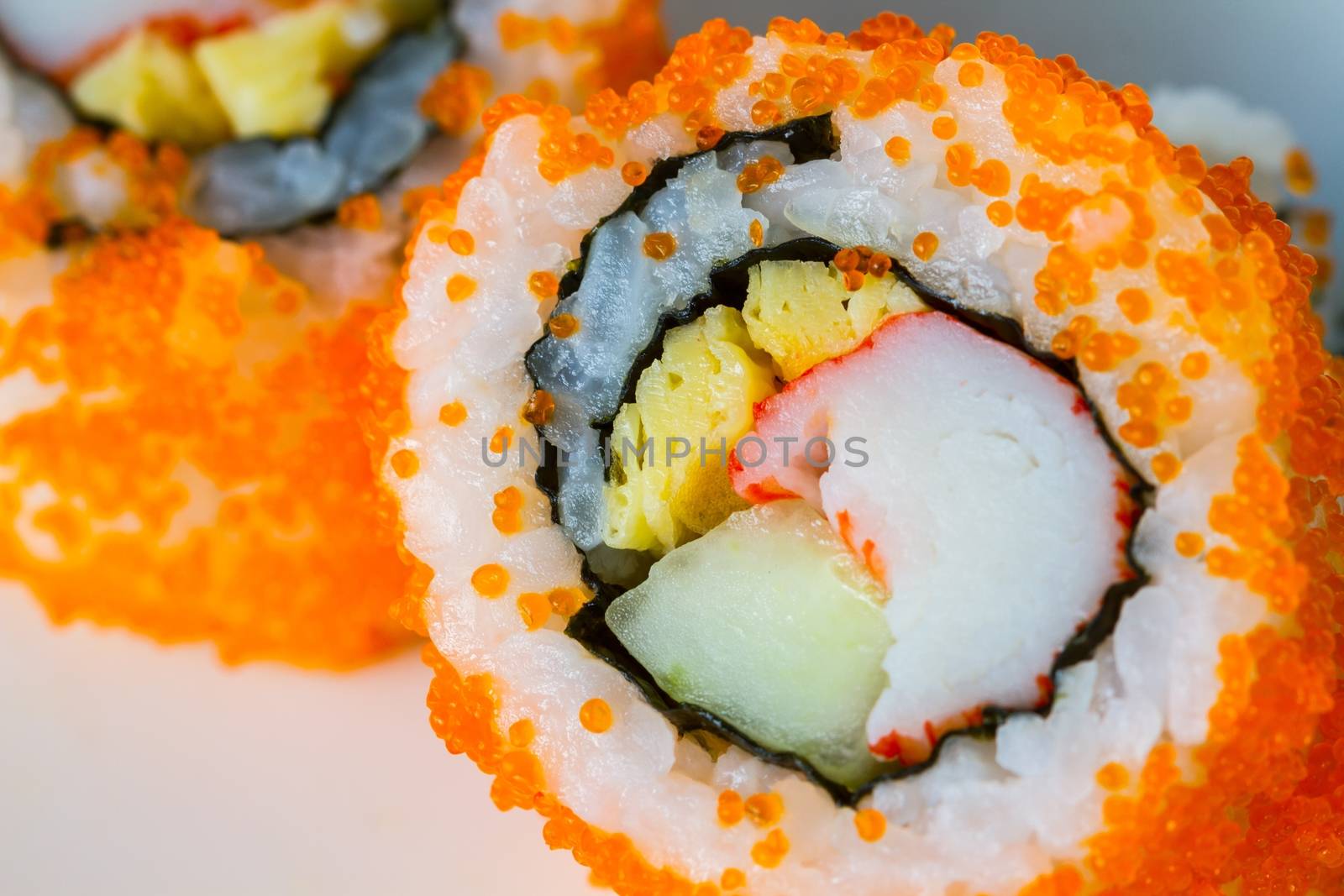 extreme close-up California Maki Sushi with Masago - Roll made of Crab Meat, egg, Cucumber inside. Masago (smelt roe) outside, soft focus, middle focused