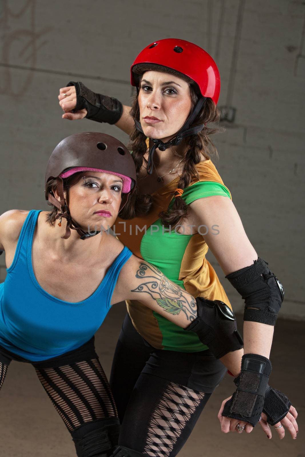 Pretty roller derby skater with tattoo and partner posing