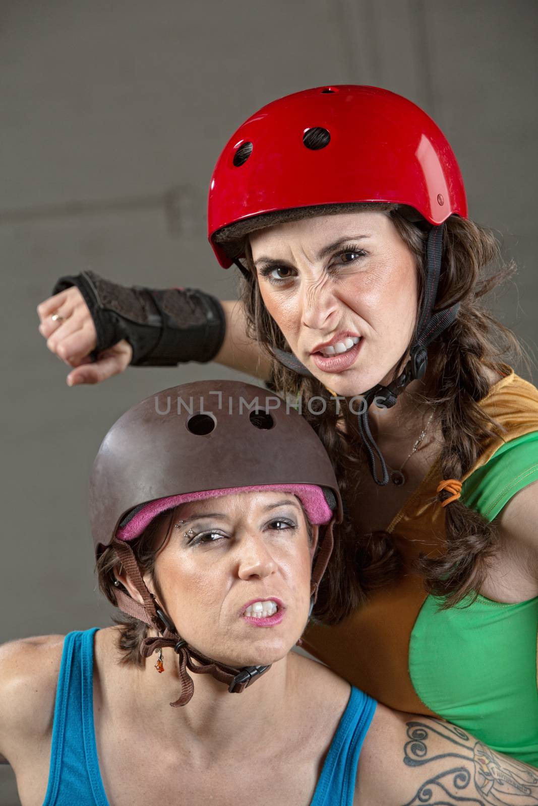 Two tough female roller derby skaters with clenched teeth