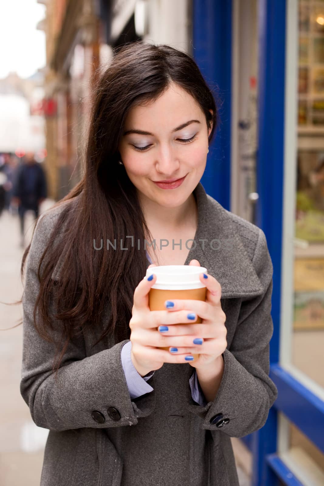 young woman holding a coffee in the street