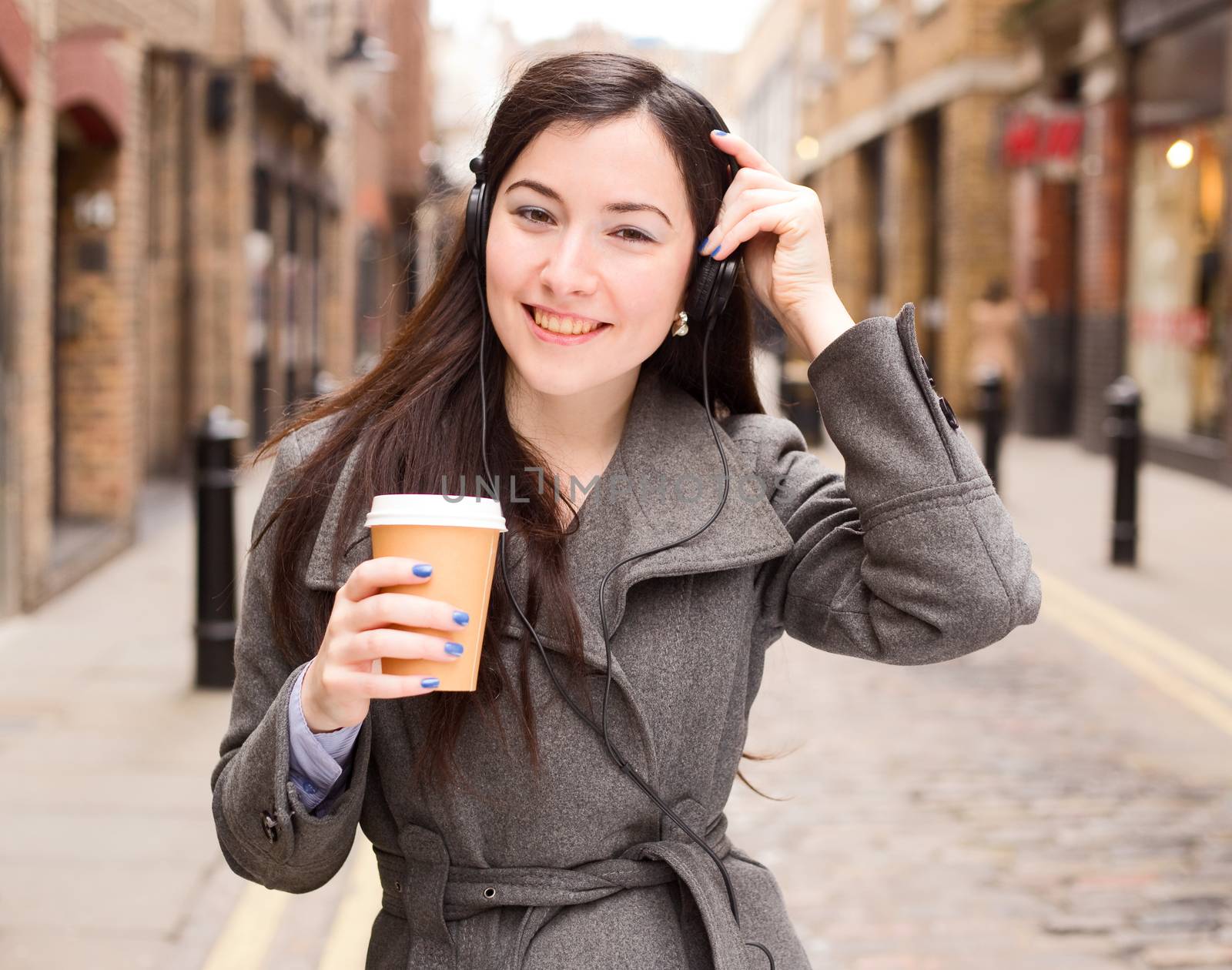 young woman listening to music with a coffee
