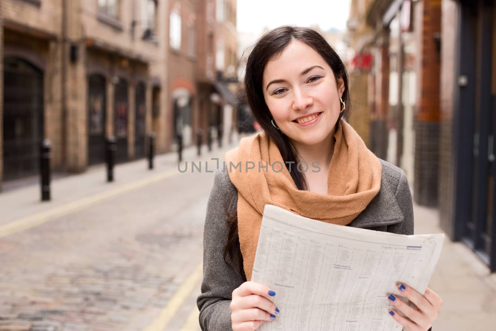 young woman reading a newspaper in the street