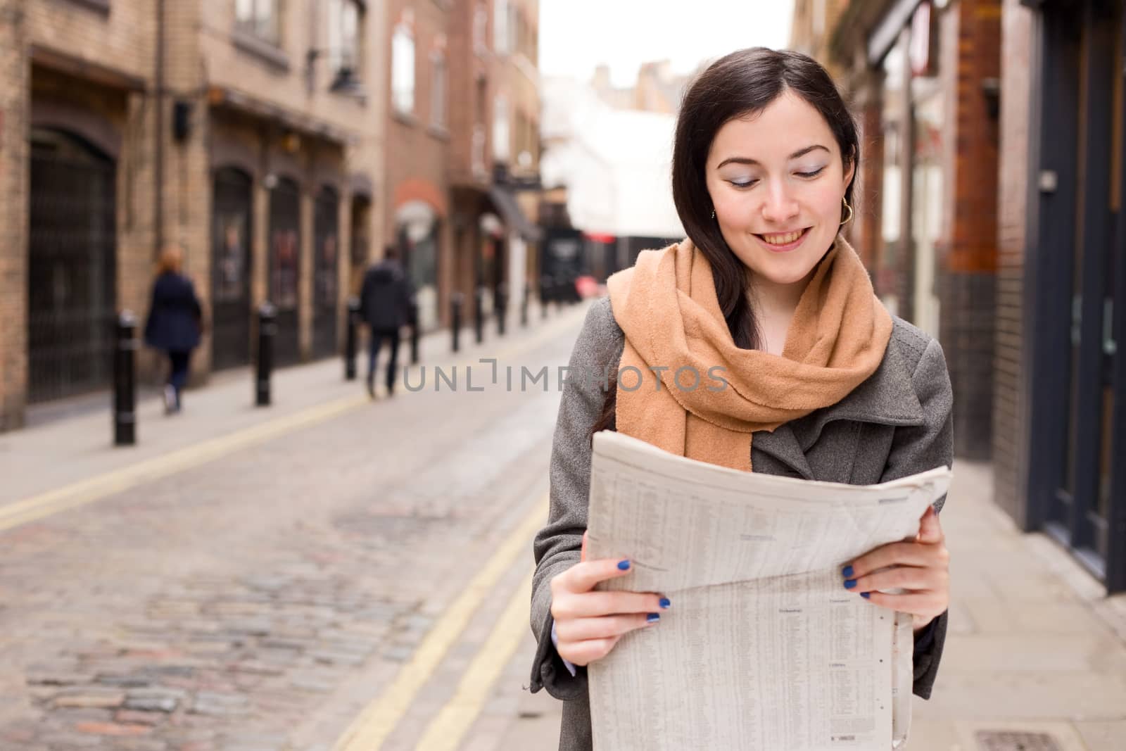 young woman reading her paper in the street