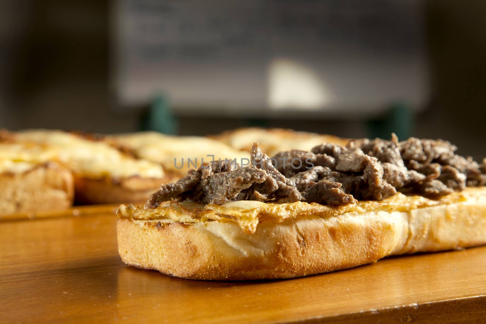 toasted open faced beef steak sandwich with melted mozzarella cheese