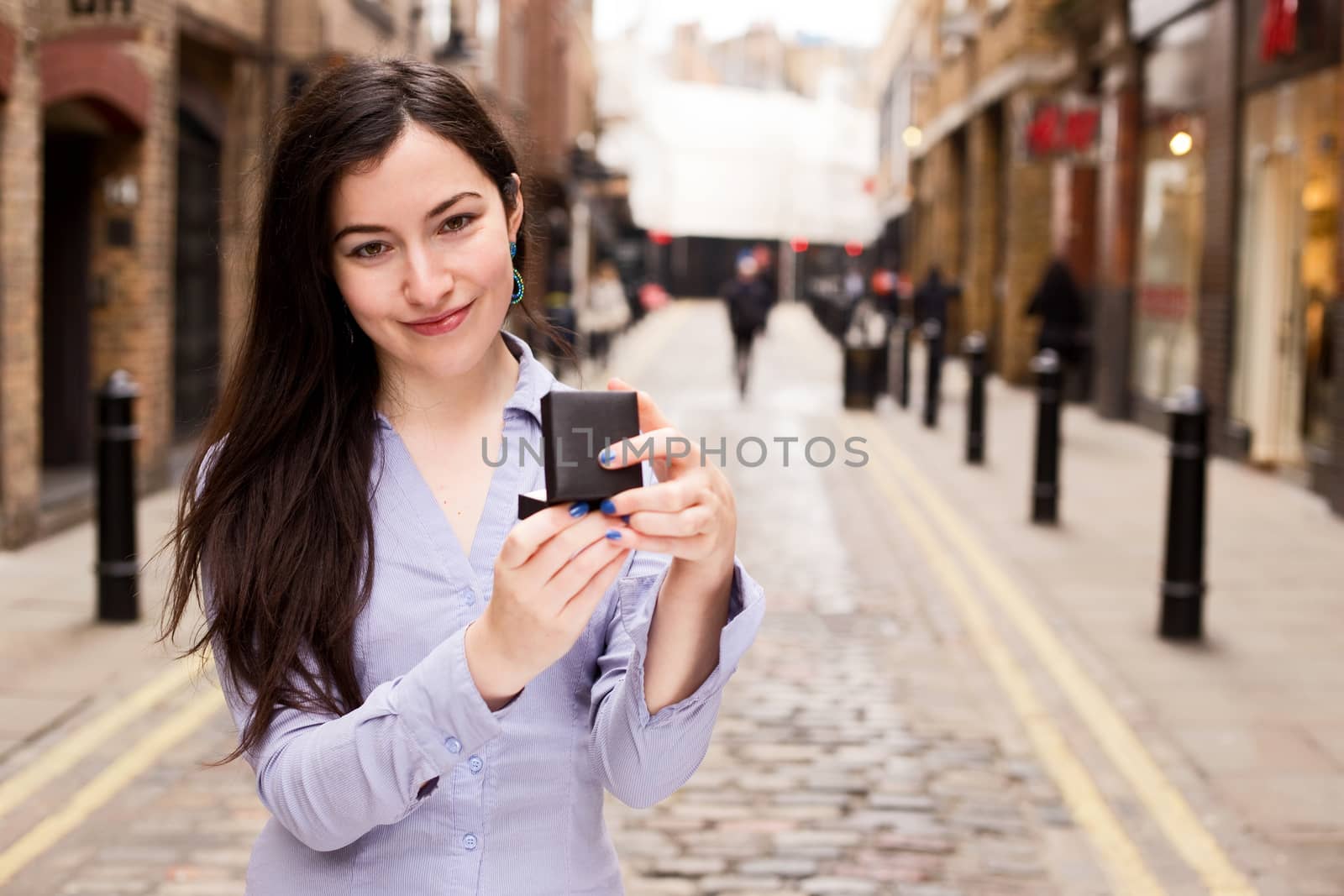 A young woman holding an engagement ring looking unimpressed