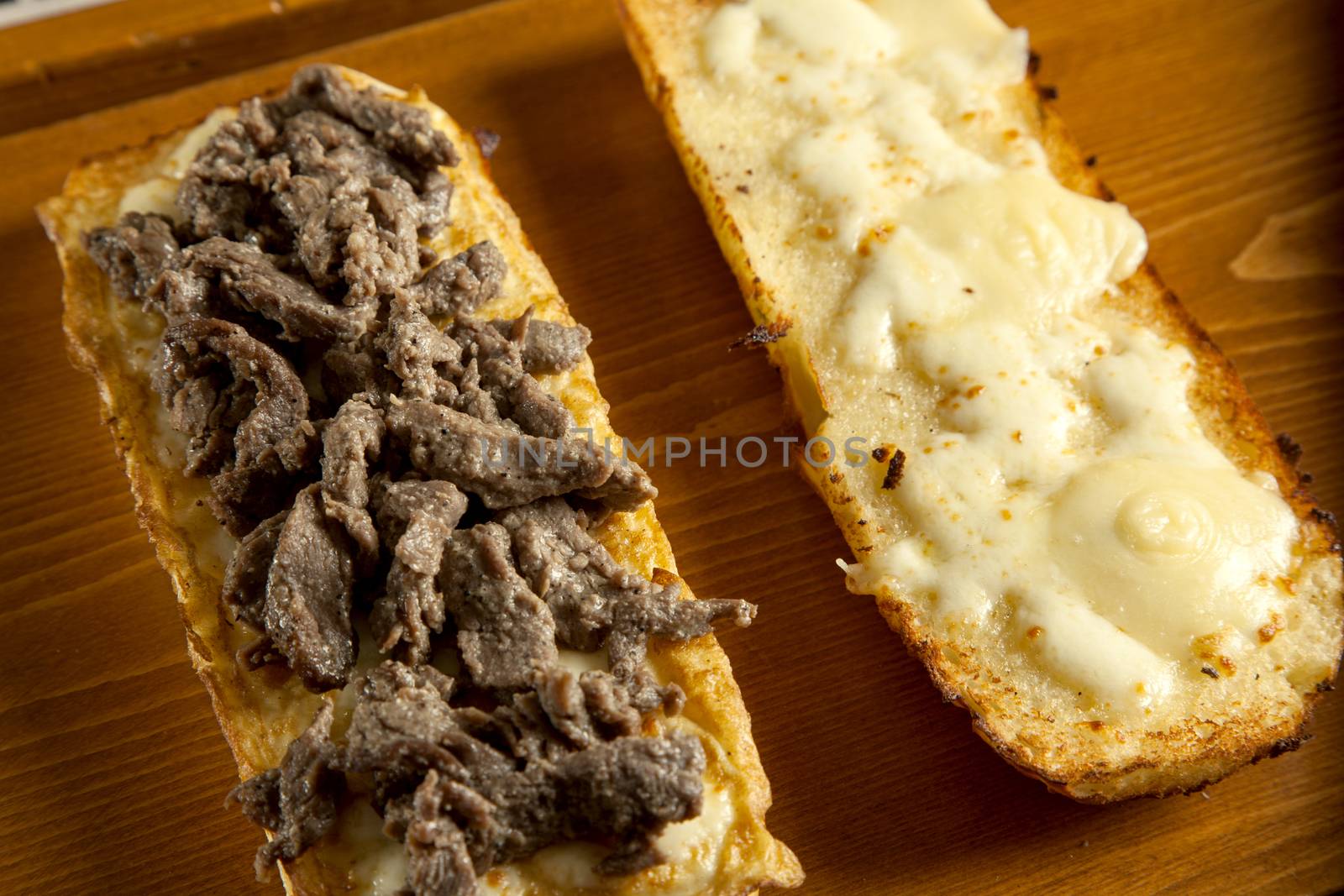 toasted open faced beef steak sandwich with melted mozzarella cheese