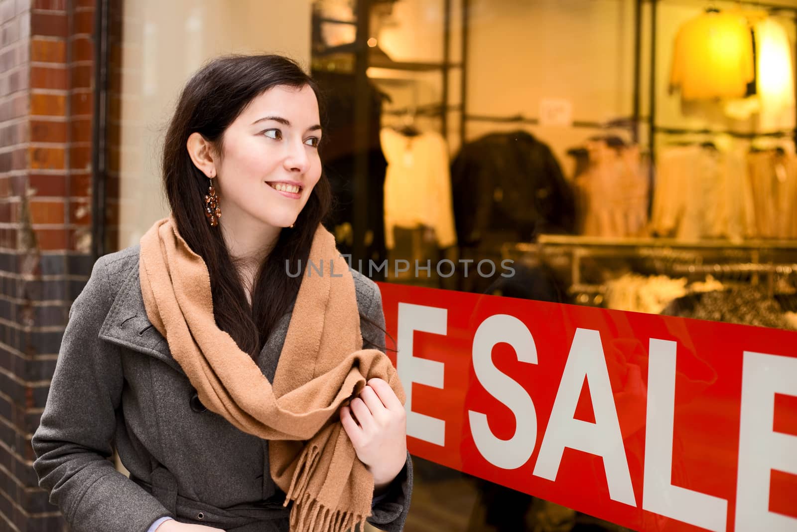 young woman looking in a shop window during the sales