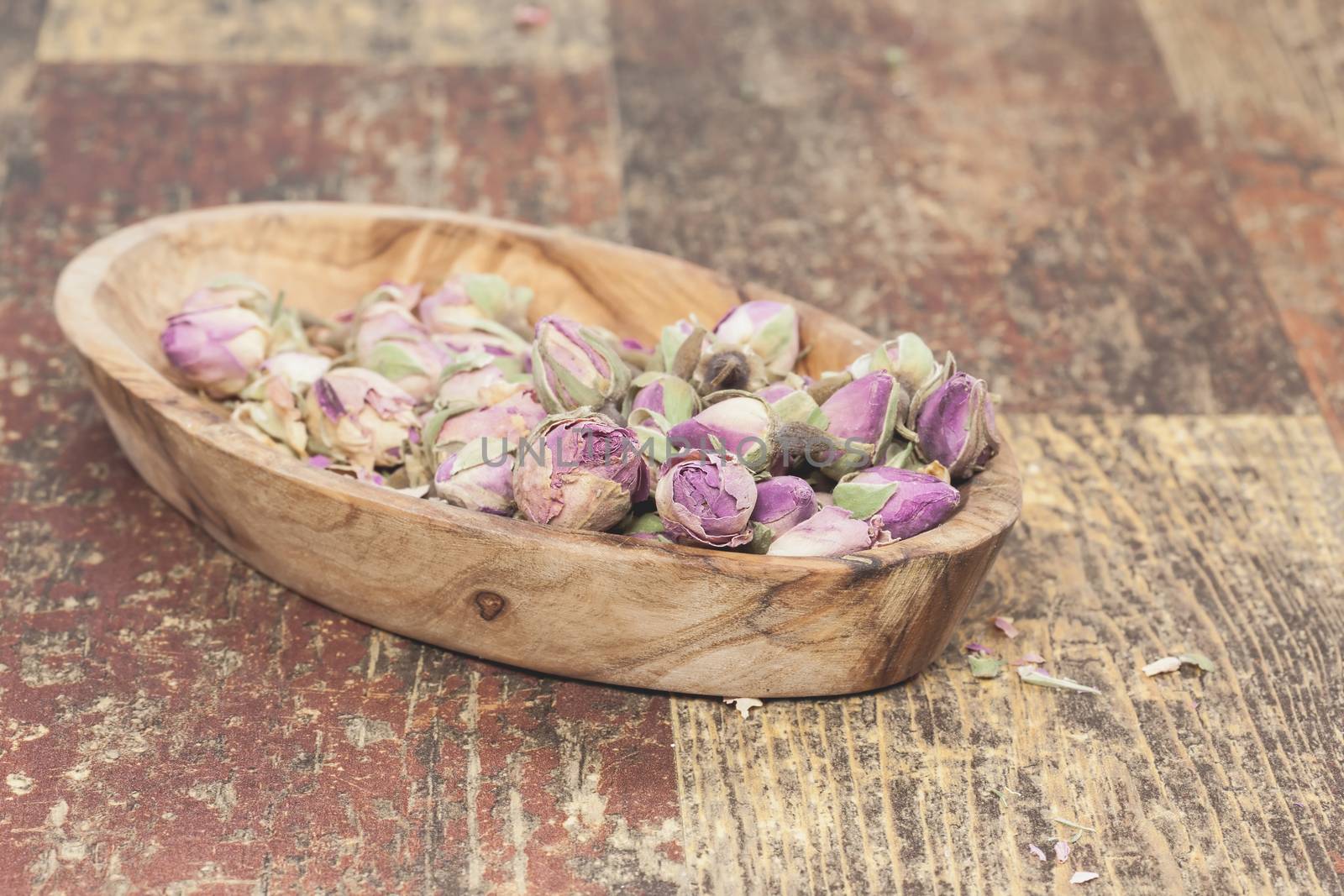 Pretty little edible violet rose buds, on old wooden table . Macro photograph with shallow depth of field. Done with a vintage retro filter