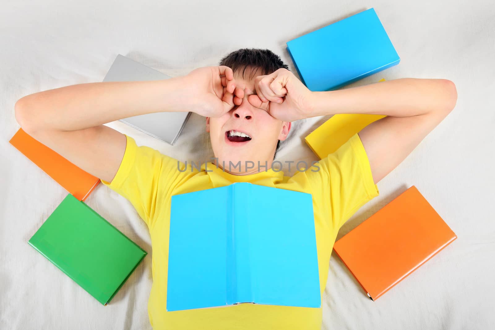 Tired Teenager Yawn with a Books on the Bed