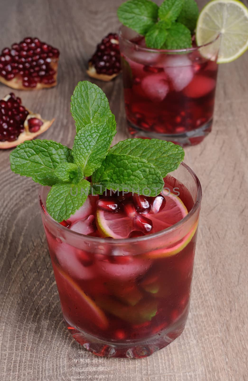 Pomegranate cocktail with slices of lime, mint and ice