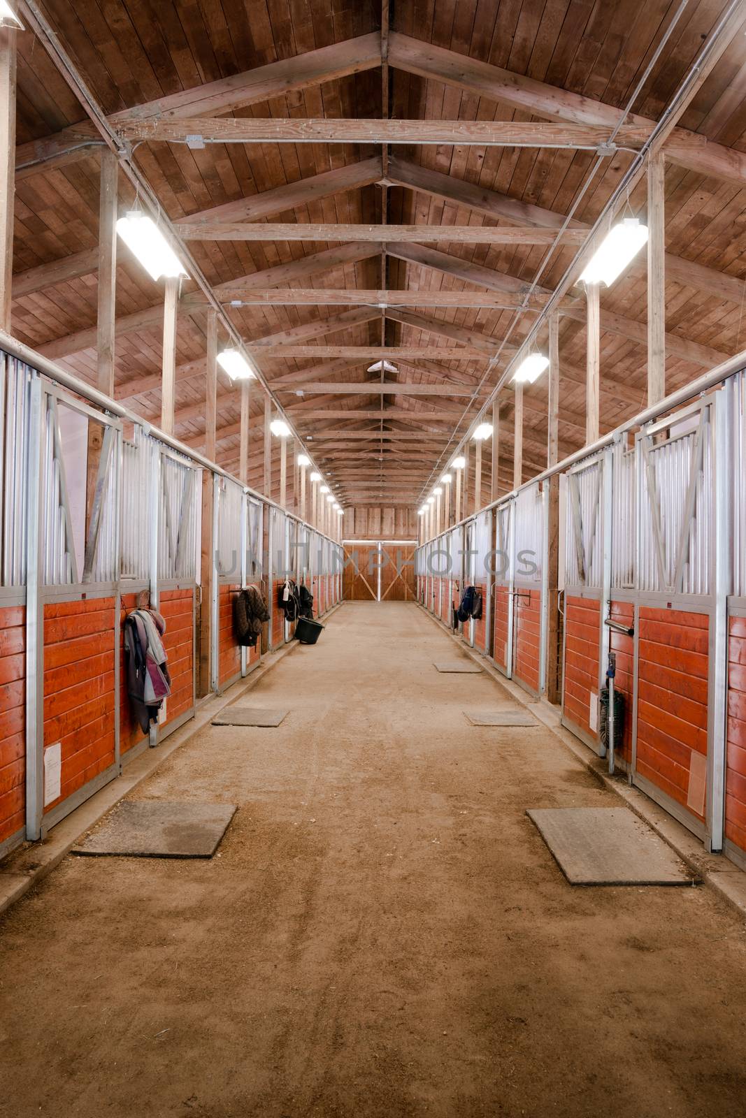 The center path through a horse barn light at the end of the tunnel