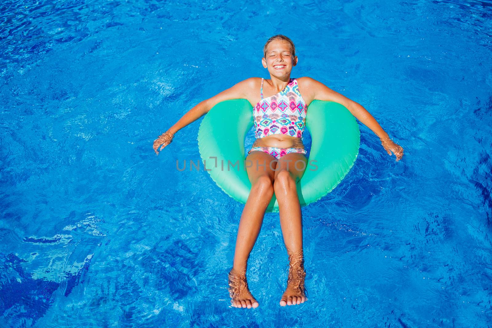 Funny girl swims in a pool in an green life preserver