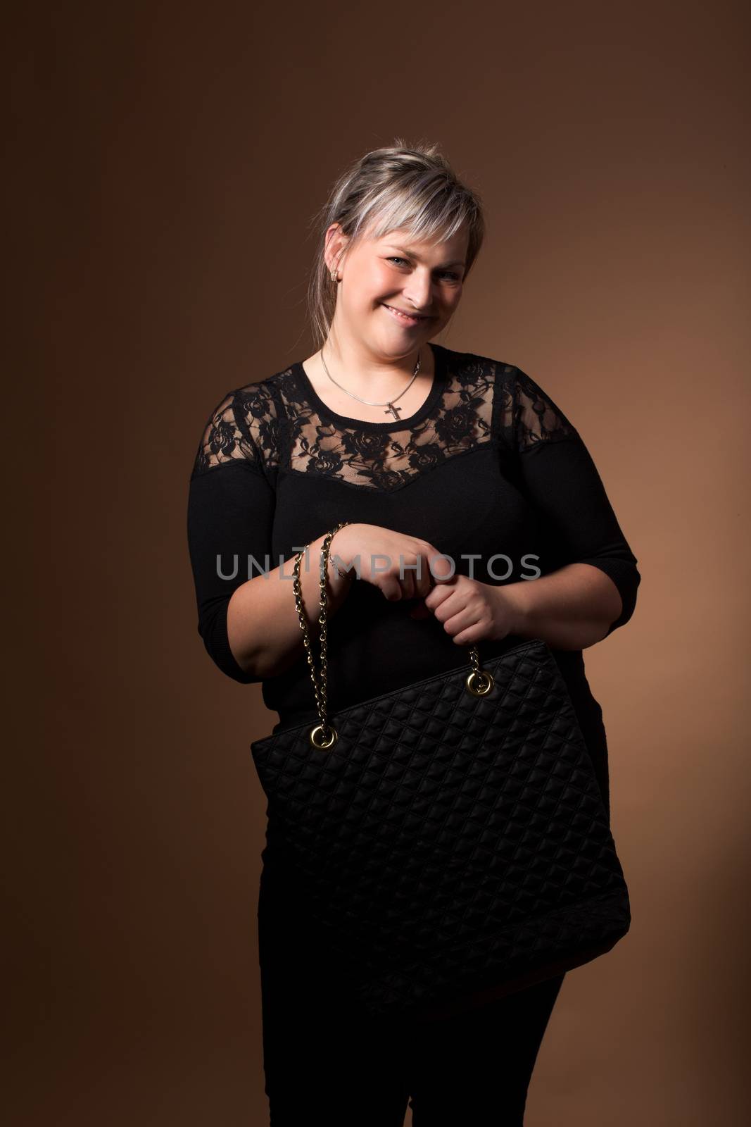 portrait of beautiful smiling plus size young blond woman posing with designer handbags and black dress