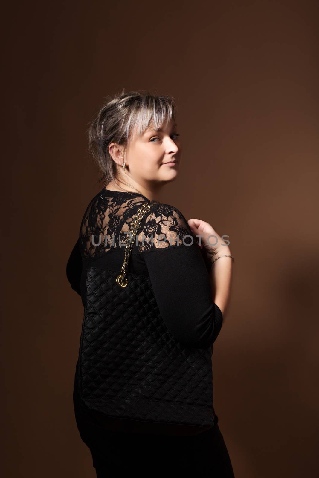 portrait of beautiful smiling plus size young blond woman posing with designer handbags and black dress