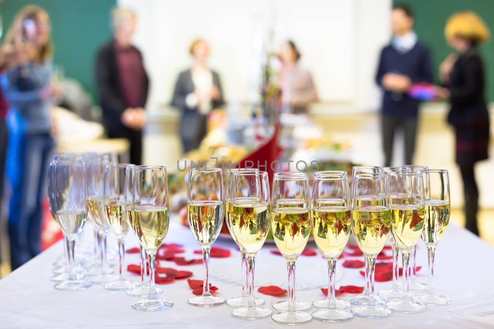 Banquet event. Waiter pouring champagne into glass. Table with the wineglasses, snacks and cocktails.