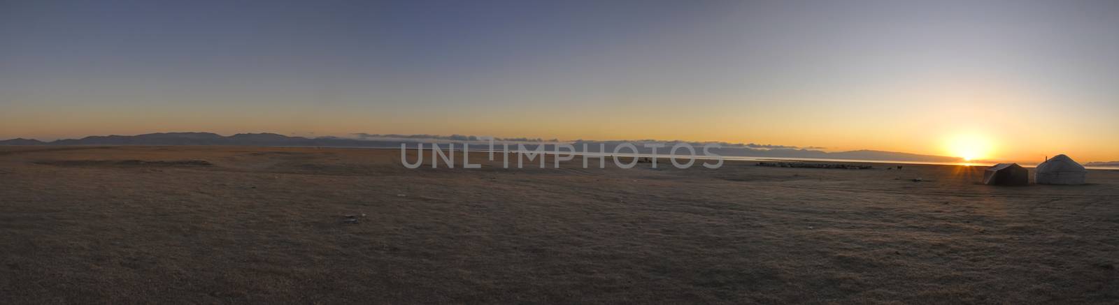 Scenic panorama of sunset on green grasslands in Kyrgyzstan with traditional nomadic yurt