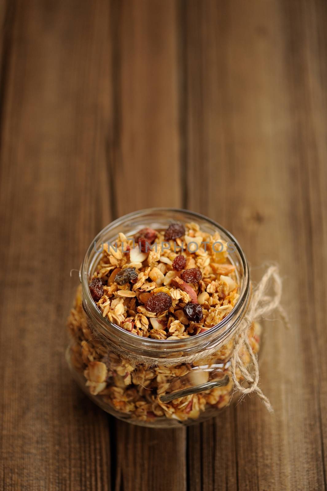 Granola in jar with packing-twine on wooden background with space selective focus vertical