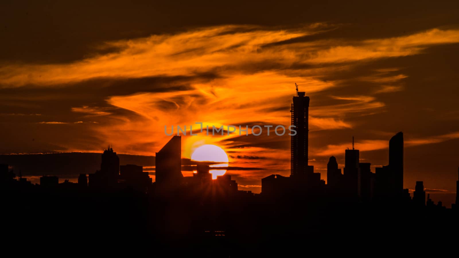 The giant beautiful sun setting behind the sky scrapers of New York City