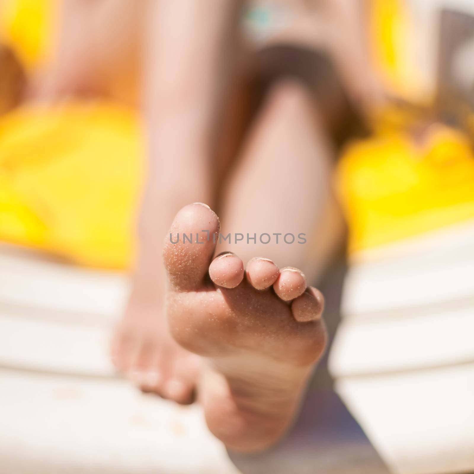 Young woman feet at the beach by sarymsakov