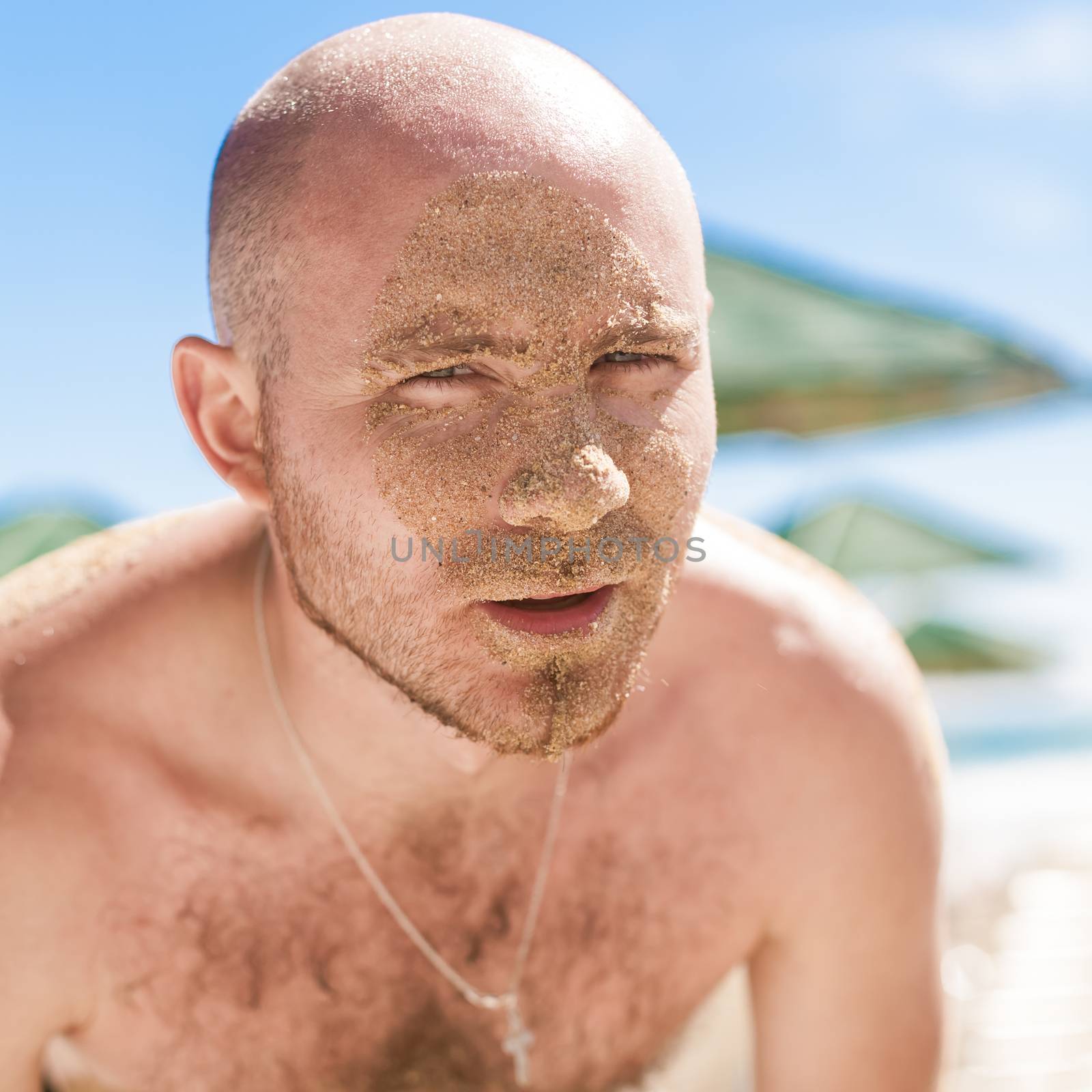 Half face of a handsome man covered with sand. Bulgaria, Black Sea