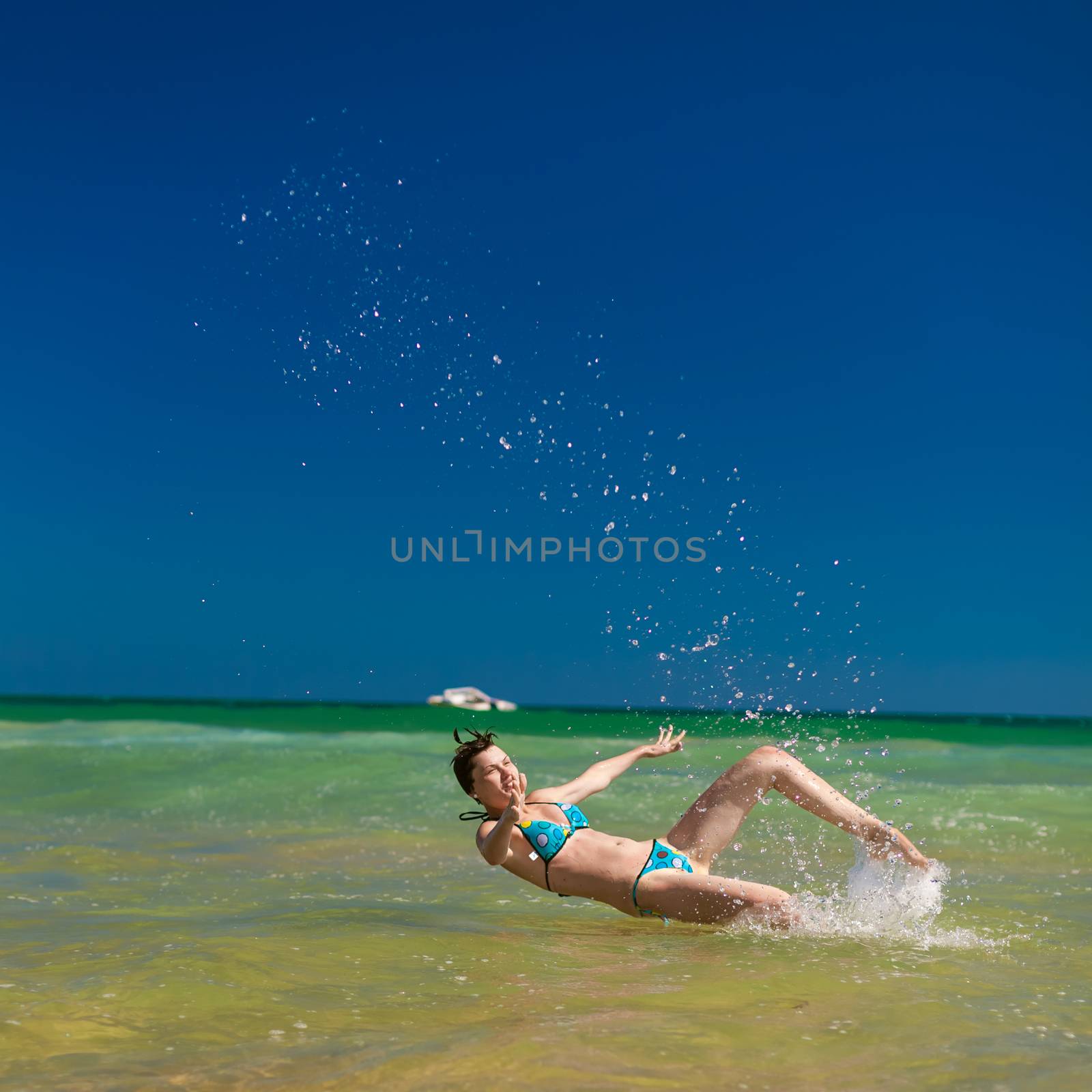 Yong happy woman splashing water in the ocean