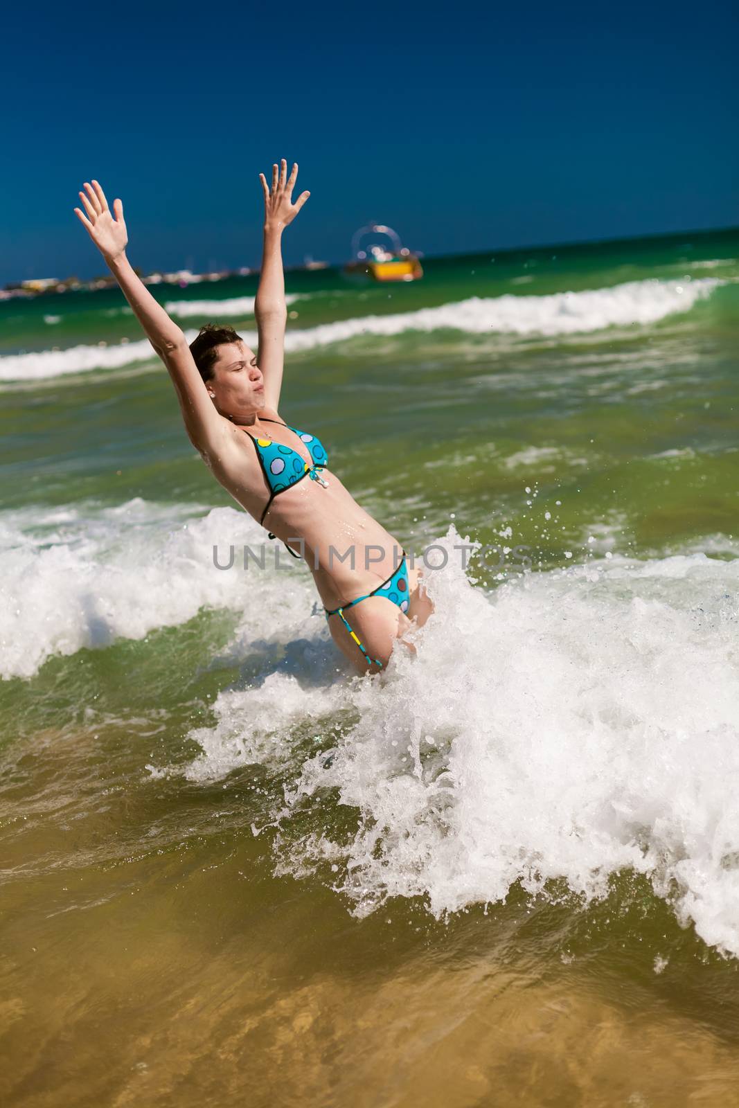 Yong happy woman splashing water in the ocean