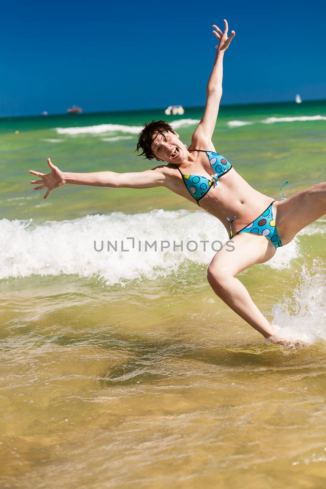 Yong happy woman splashing water in the ocean