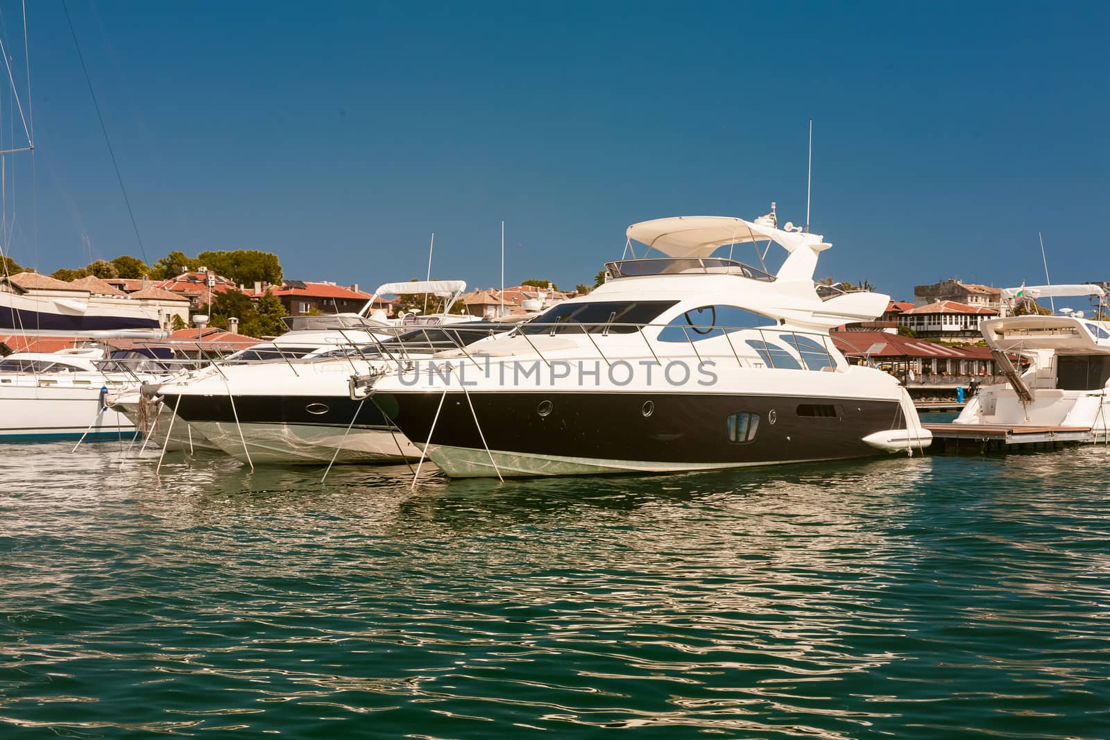 Row of luxury motorised yachts moored in a sheltered harbour, close up view of the bows