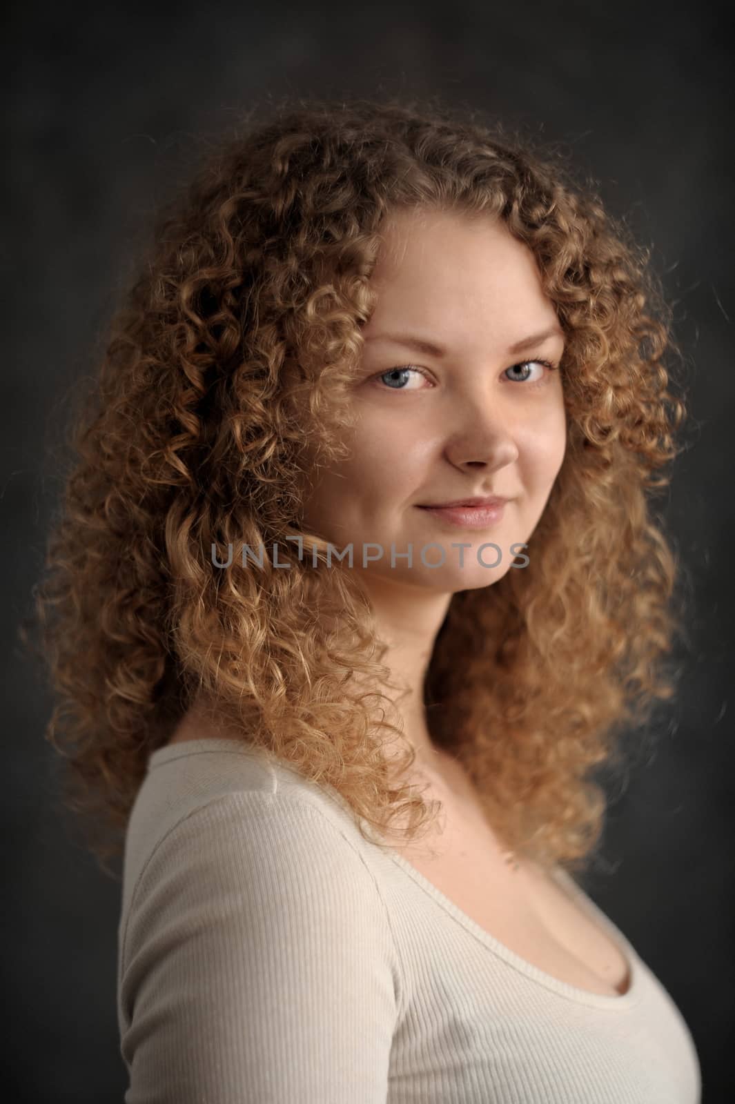 Smiling fairy woman with red curly hair, big breast, low neck decollete on dark grey background vertical portrait