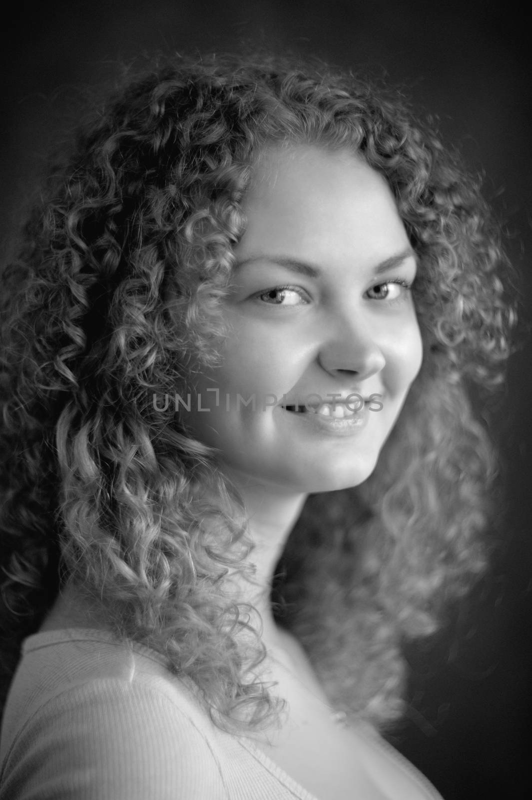 Smiling fairy woman with curly hair, big breast on dark grey background black&white vertical portrait