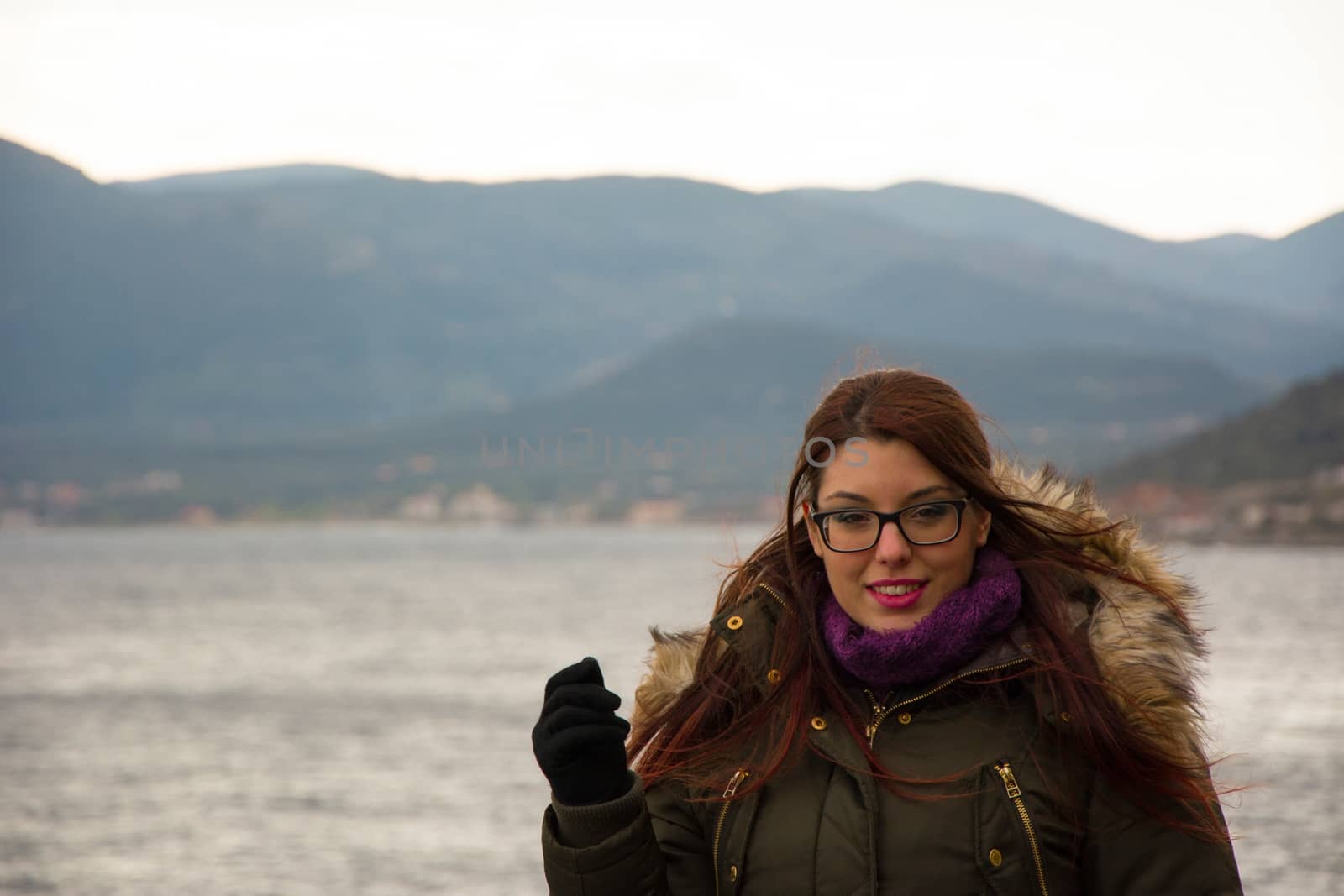 A young girl on a winter excursion standing in front of the sea.