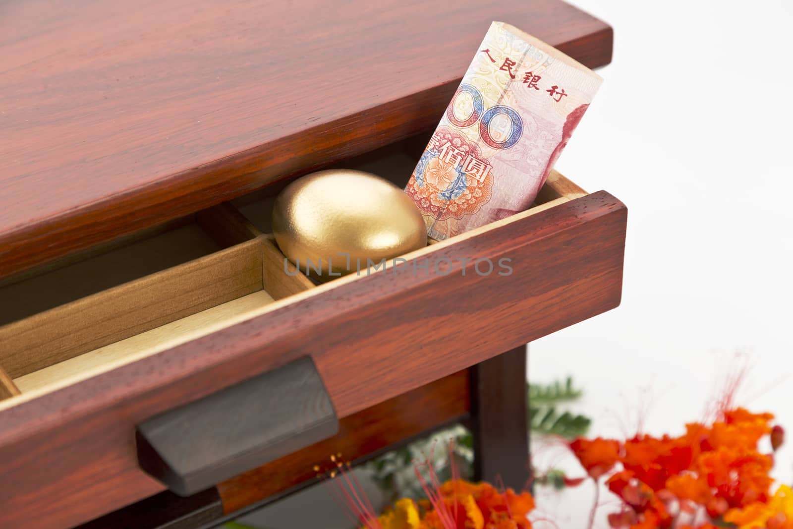 Chinese yuan currency and gold nest egg nestled in wood drawer