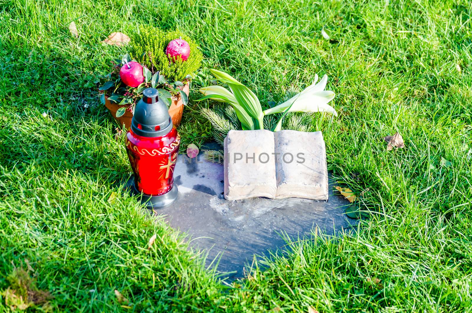 View of a lawn grave memorial stone with a cemetery with flowers.