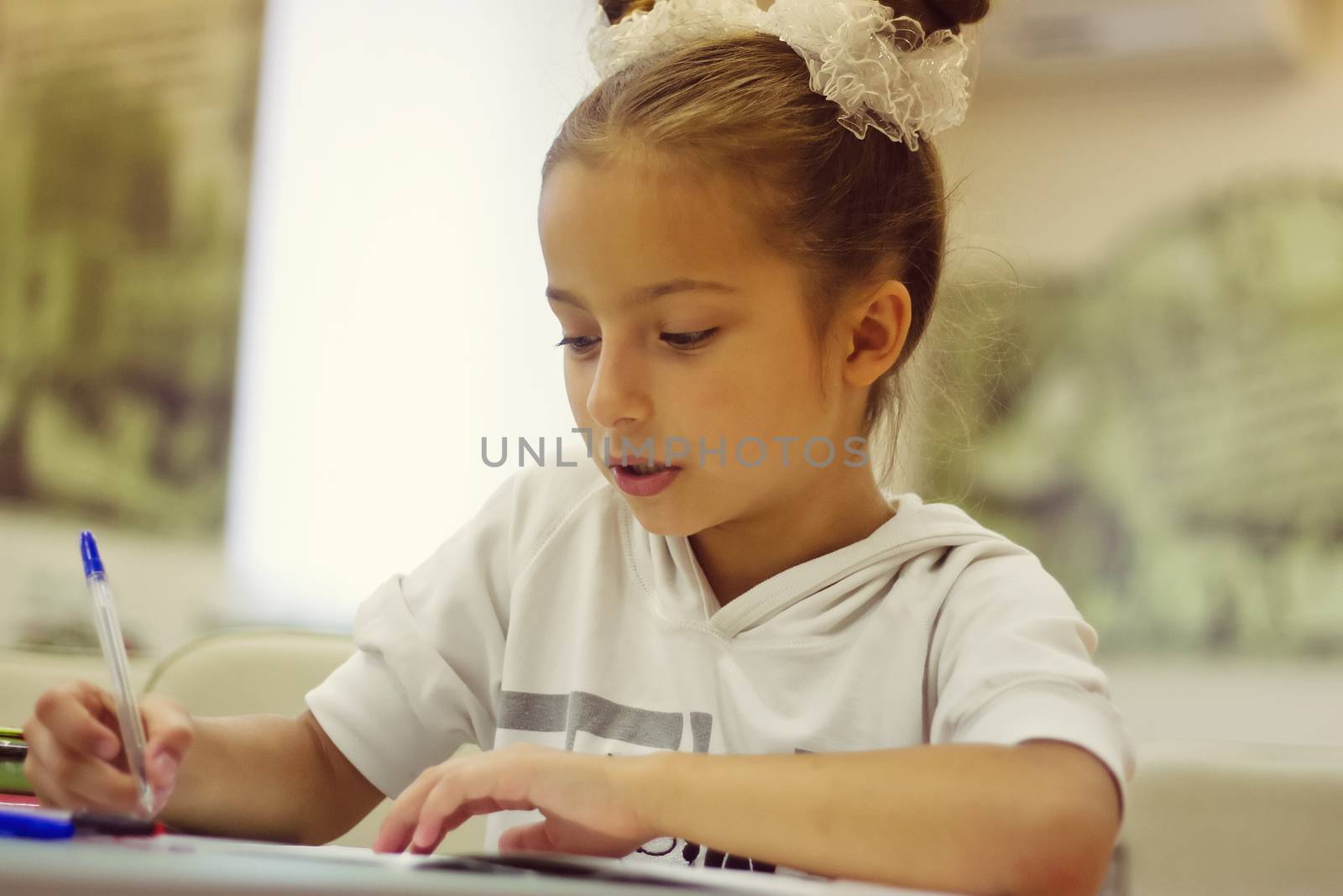 first grader girl writes a pen in notebook