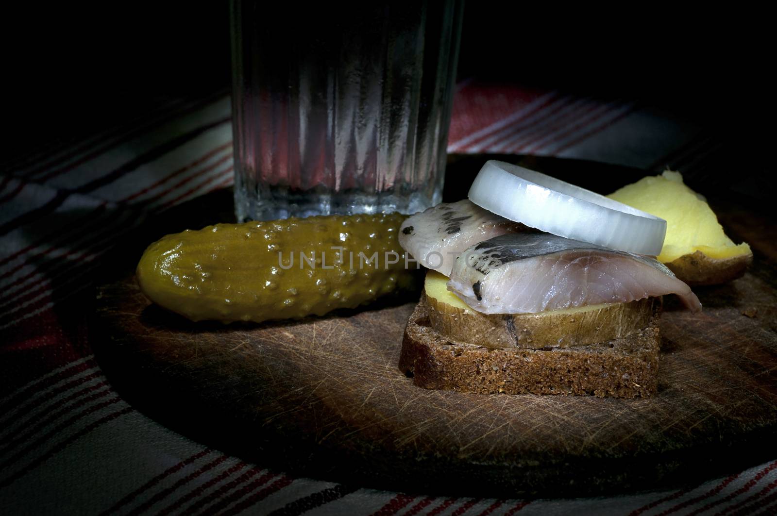 Sandwich made of herring on boiled jacket potato and rye bread served with vodka