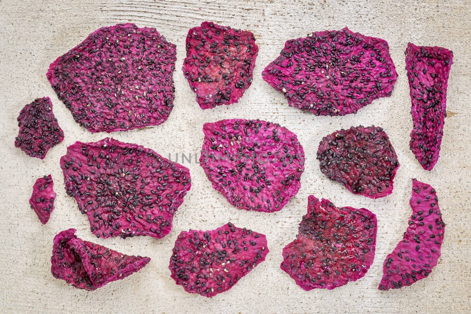 slices of dried red dragon fruit against rustic white painted wood