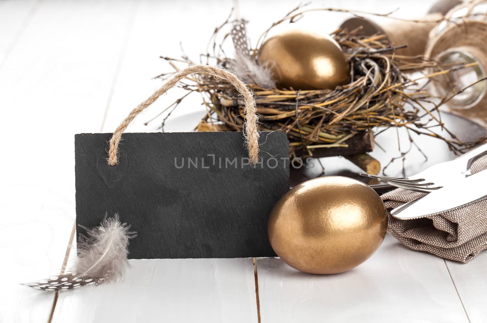 table decoration on white wooden background with chicken golden egg, with blackboard with space for text
